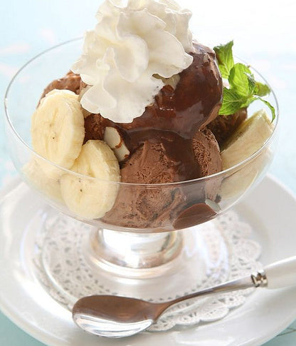 Coupe glacée au chocolat garnie de bananes fraîches et de crème chantilly.