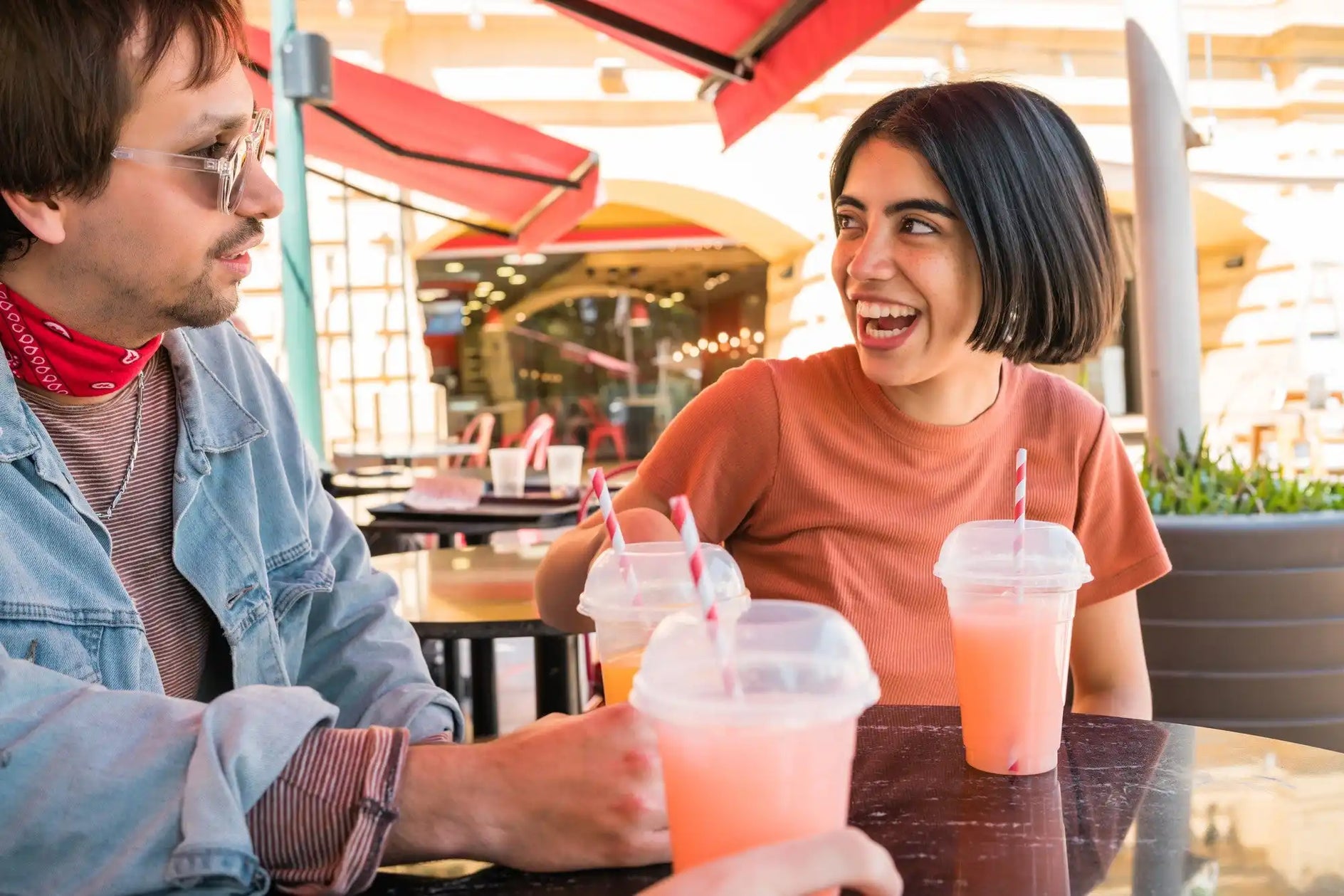 Deux amis savourant des boissons roses froides ensemble dans un café en plein air.