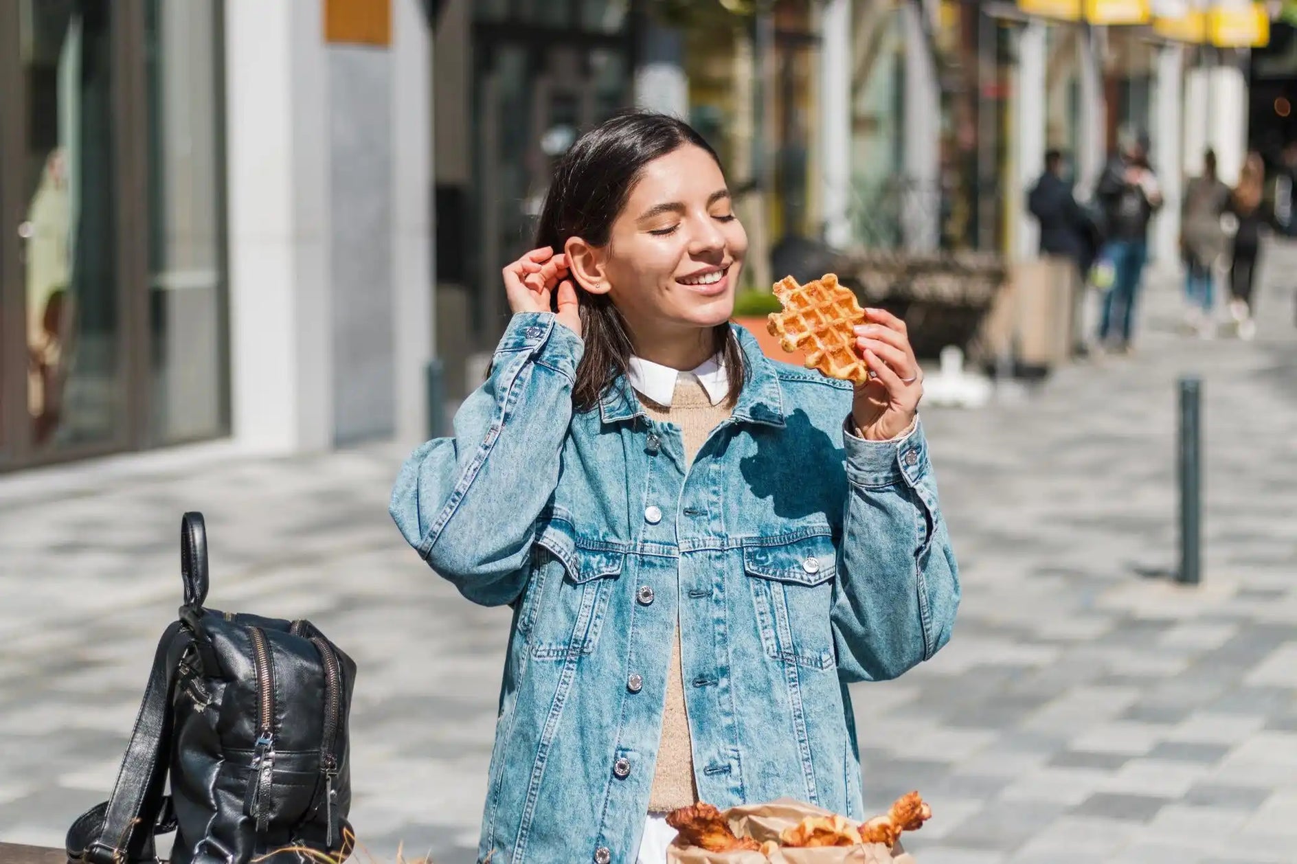 Quelqu'un dégustant une part de pizza tout en portant une légère veste en denim.